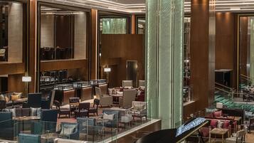 A spacious lobby with a grand piano, comfortable seating, and a modern chandelier.