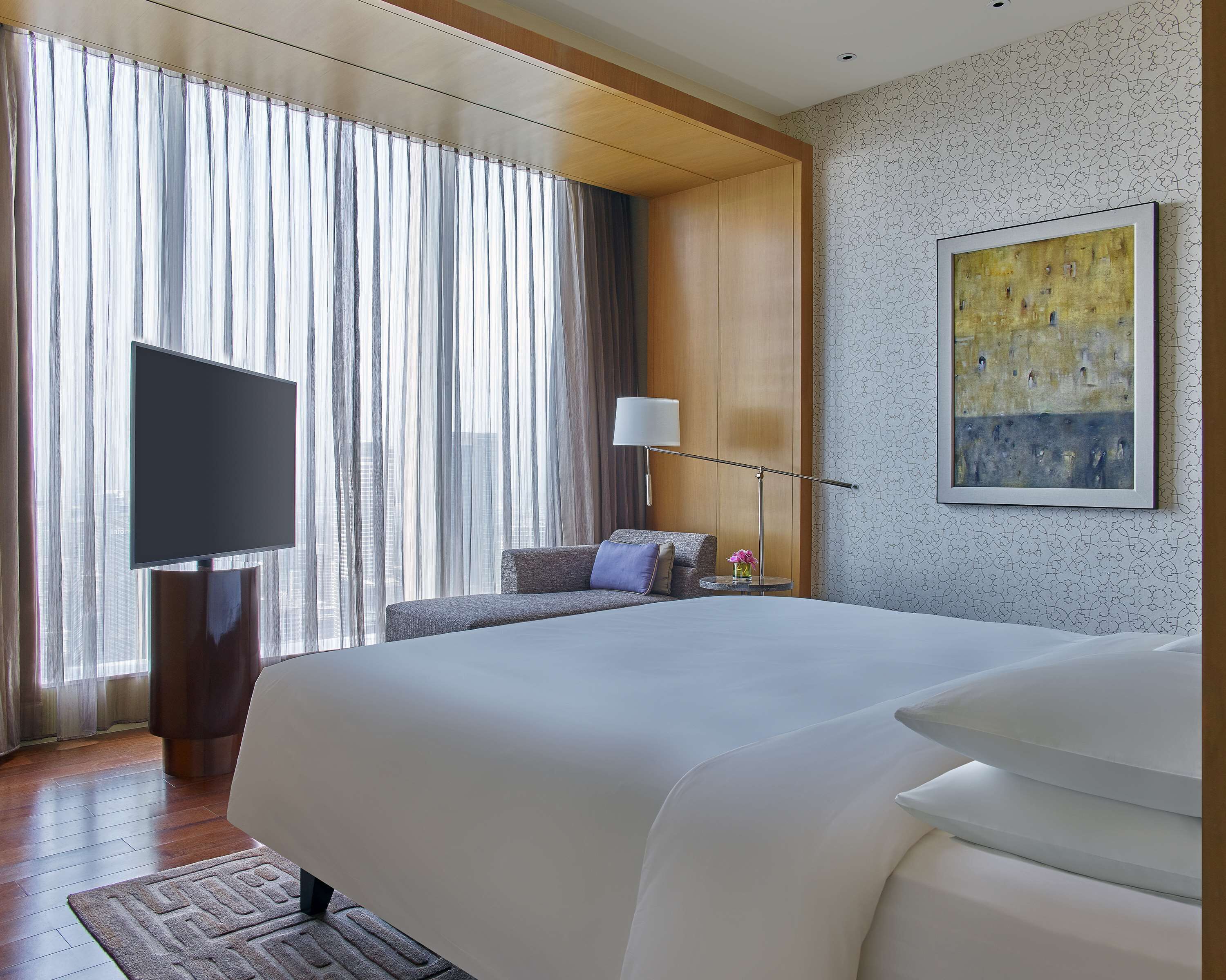 Une chambre d’hôtel avec un grand lit, un téléviseur à écran plat, un bureau et un tableau au mur.