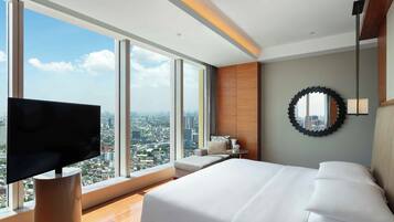 A modern hotel room with a large bed, a TV, and a city view.