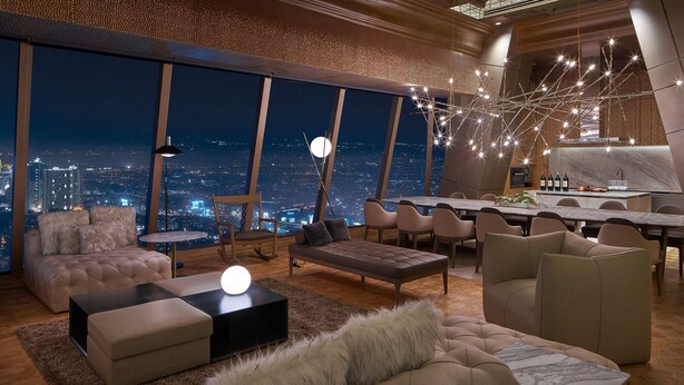 Interior de un rascacielos con vistas panorámicas a la ciudad, un comedor y muebles modernos.