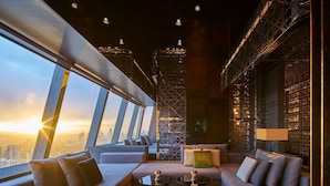 Un salón de hotel moderno con vistas a la ciudad, muebles contemporáneos y suelo estampado.