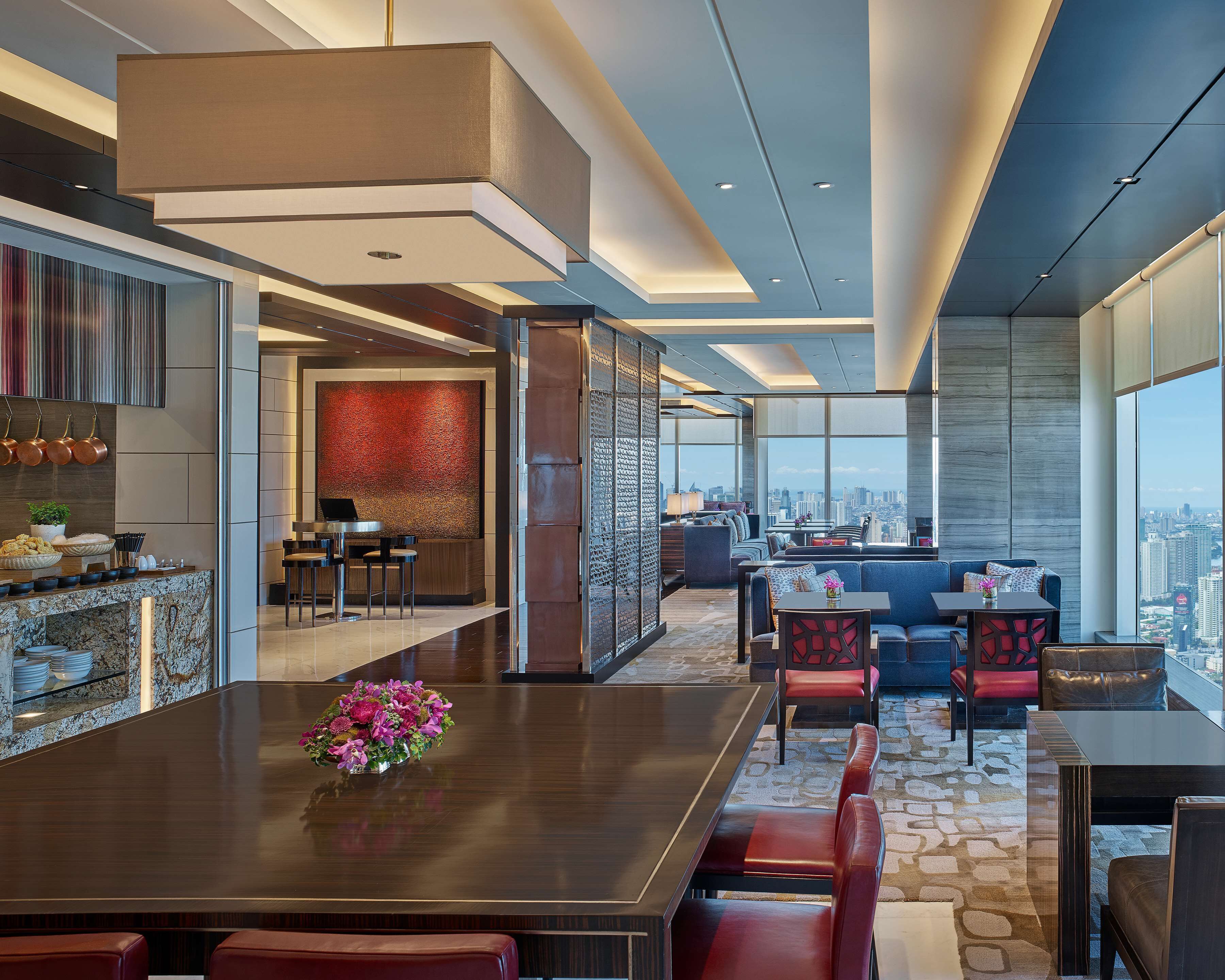 Un moderno vestíbulo de hotel con una amplia mesa de comedor, zona de estar y vista a la ciudad.