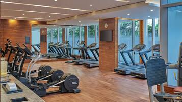 A gym with exercise equipment, wooden flooring, and large windows.