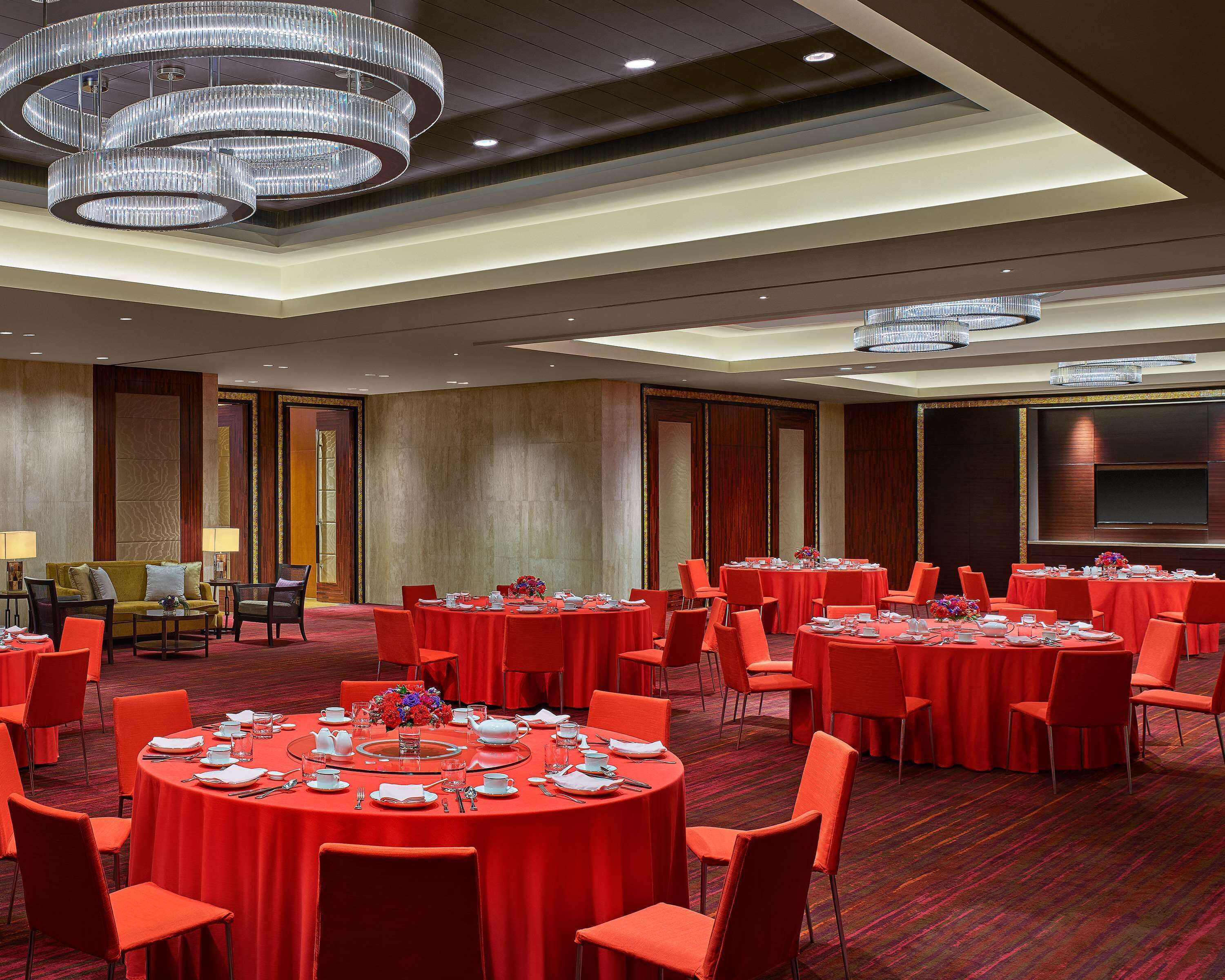 A conference room with multiple tables set for a meeting, equipped with chairs, tables, and a large screen.