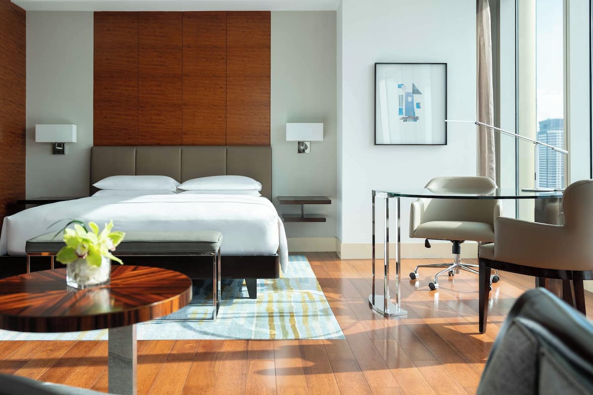 A modern hotel room with a large bed, a desk, and a chair.