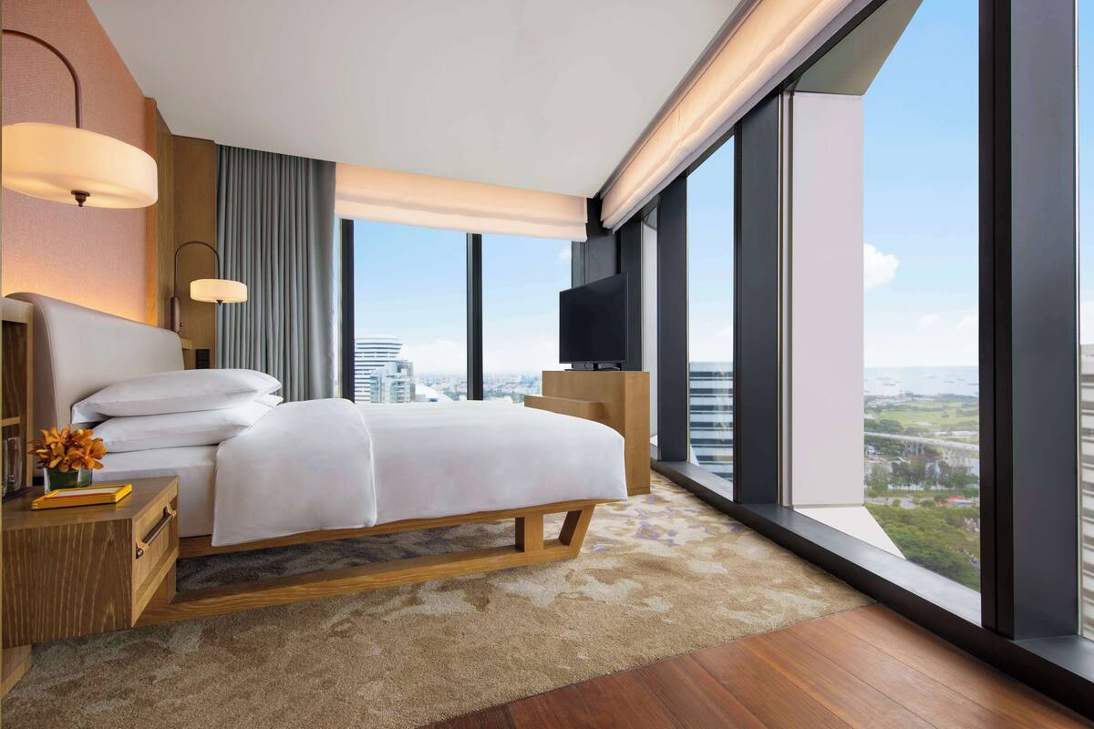 A modern hotel room with a large bed, a TV, and a city view.