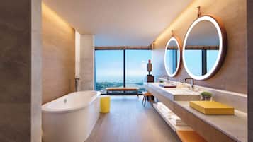 Un baño moderno con una bañera independiente, un banco, un espejo grande y vistas a la ciudad.