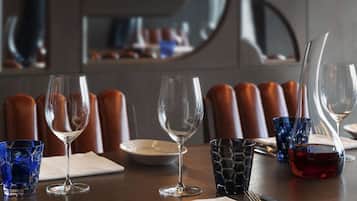 A dining table set with wine glasses, plates, and cutlery, with a modern interior design and leather chairs.