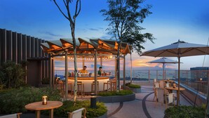 An outdoor bar area with seating and a view of the cityscape at dusk. - ANDAZ SINGAPORE, BY HYATT (Singapore)
