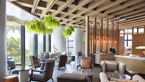 A modern hotel lobby with a mix of seating areas, a kitchen, and large windows offering views of greenery. - ANDAZ SINGAPORE, BY HYATT (Singapore)