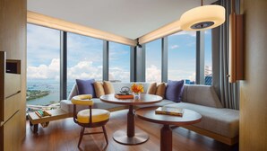 A modern hotel room with a large window offering a city view, a sofa, two round tables, and a small wooden side table. - ANDAZ SINGAPORE, BY HYATT (Singapore)