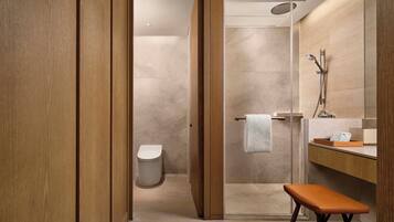A modern bathroom with a wooden vanity, a glass shower enclosure, and a bench.