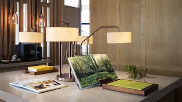 A well-lit reception desk with a modern lamp, a magazine rack, and a small plant.
