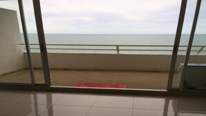 A room with a view of the sea through a sliding glass door.