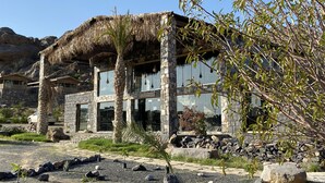A stone building with a thatched roof, a reception area, and a view of the surrounding landscape. - Sama Jabal Shams Resort (Al Hamra)