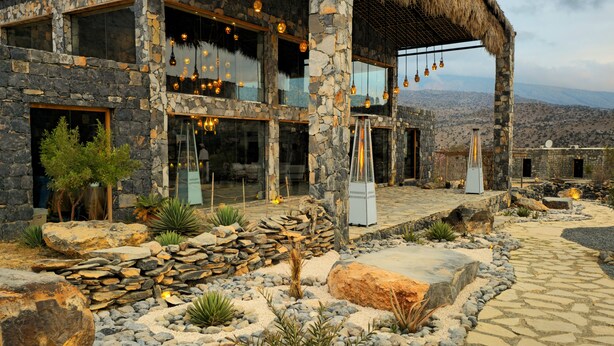 A stone building with large windows, a thatched roof, and hanging light fixtures. - Sama Jabal Shams Resort (Al Hamra)