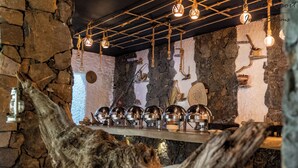 A rustic interior with stone walls, a wooden beam, and hanging light fixtures. - Sama Jabal Shams Resort (Al Hamra)