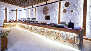 Un área de bufé con una barra de piedra, distintas estaciones de comida y un techo con diseño de cuadrícula.