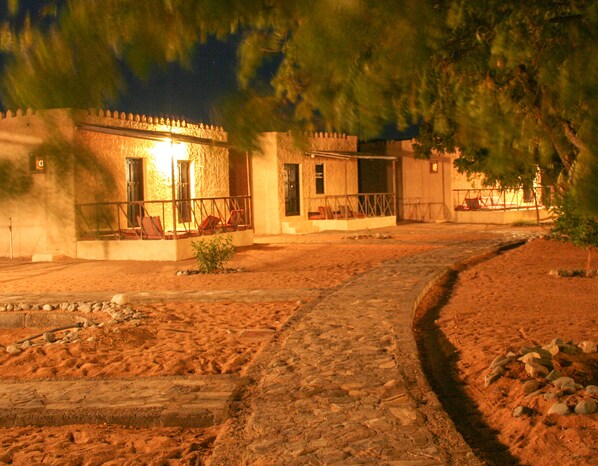 A stone pathway leading to a building with a porch and a small garden area. - Sama Al Wasil Desert Camp (Bidiya)