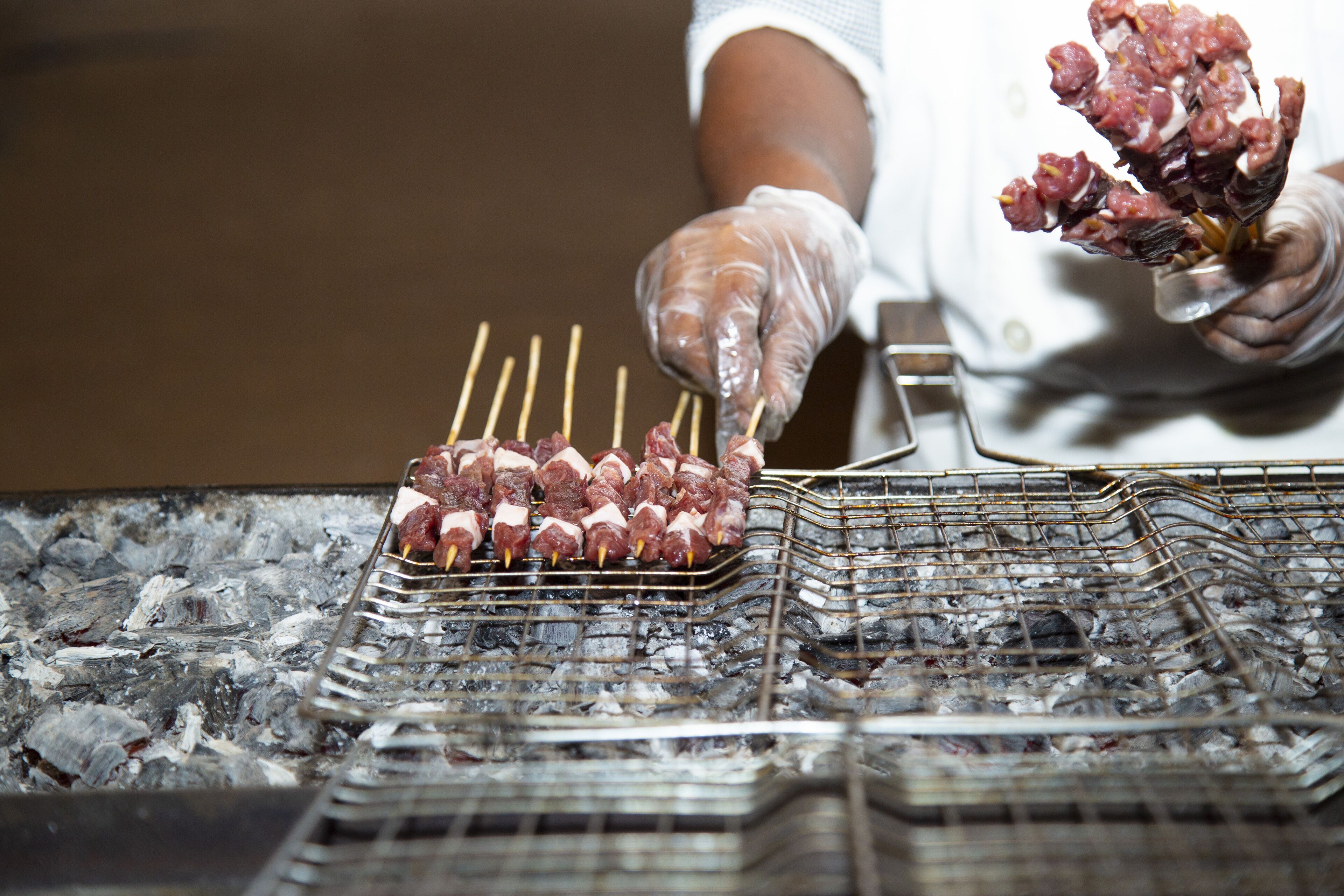 Skewers of meat being grilled on a charcoal grill.