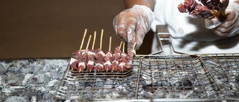 Skewers of meat being grilled on a charcoal grill.