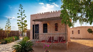Un edificio tradicional con fachada de piedra, puerta de madera y un pequeño porche con cojines rojos.