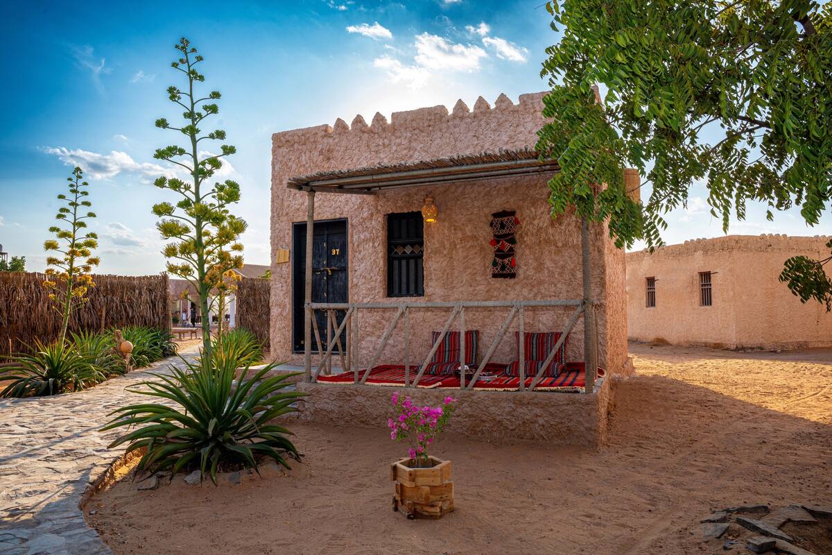 A traditional building with a stone facade, a wooden door, and a small porch with red cushions.