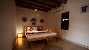 Un dormitorio acogedor con una cama de madera, una mesita de noche con lámpara, un estante en la pared con objetos decorativos y suelo de madera.