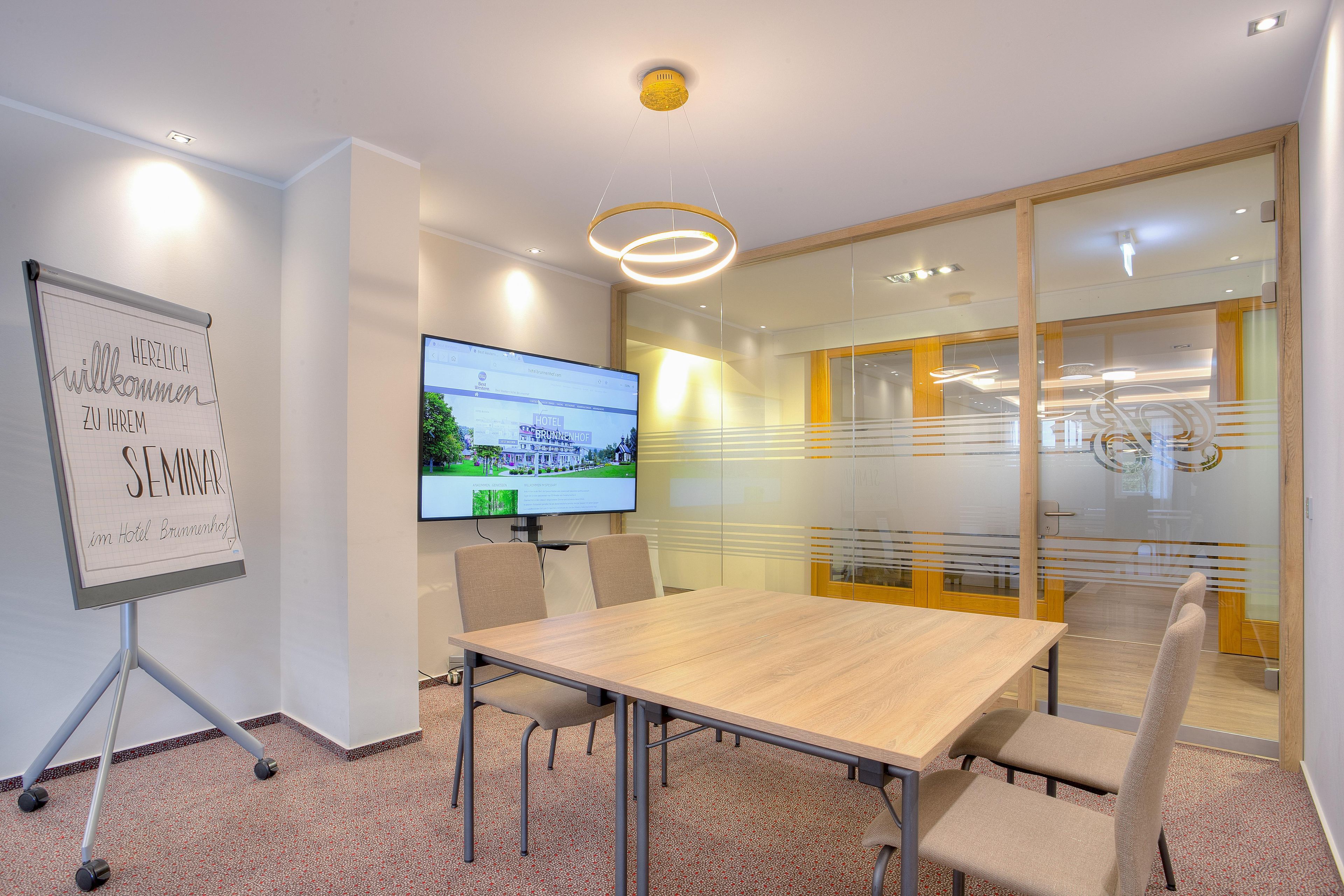 A conference room with a whiteboard, a flat-screen TV, and a glass partition.