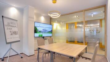 A conference room with a whiteboard, a flat-screen TV, and a glass partition.