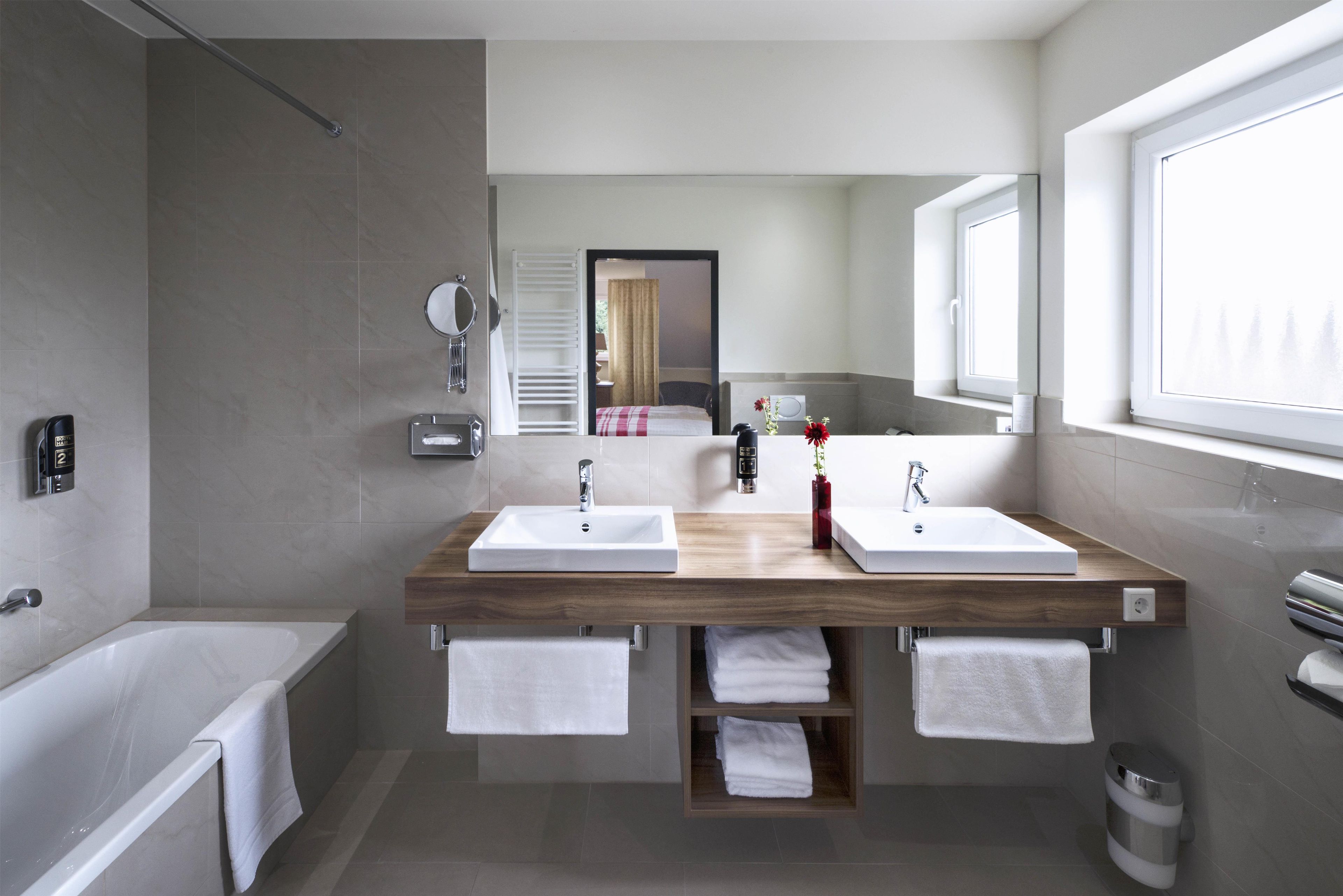 A modern bathroom with two sinks, a bathtub, and a shower.