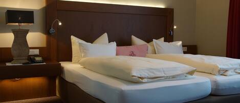 A hotel room with a double bed, two bedside tables, a lamp, and a telephone.