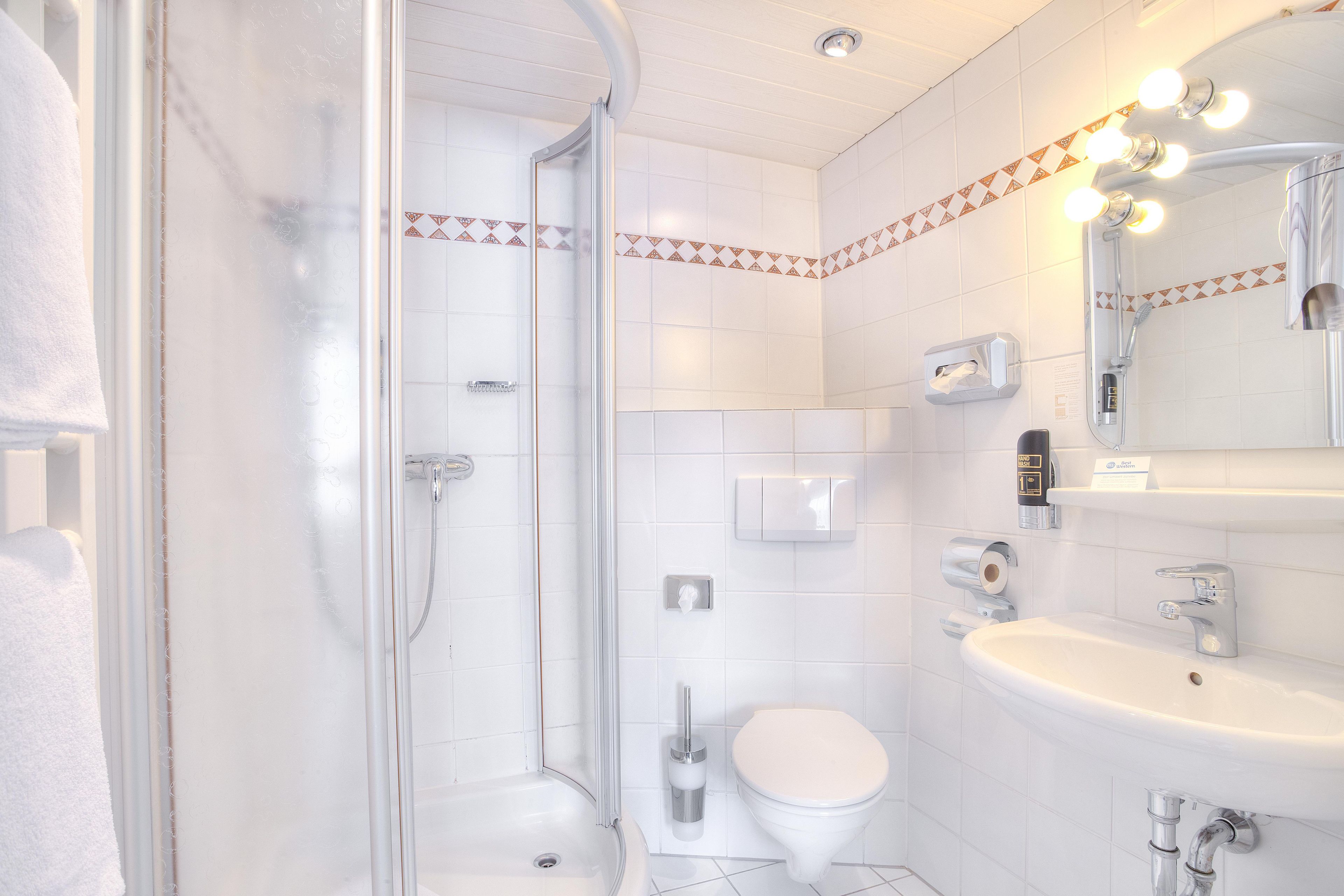Een moderne badkamer met een douche met glazen wand, een toilet en een wastafel met spiegel erboven.