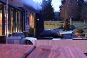Un área de comedor exterior con una parrilla, mesas y una estatua.