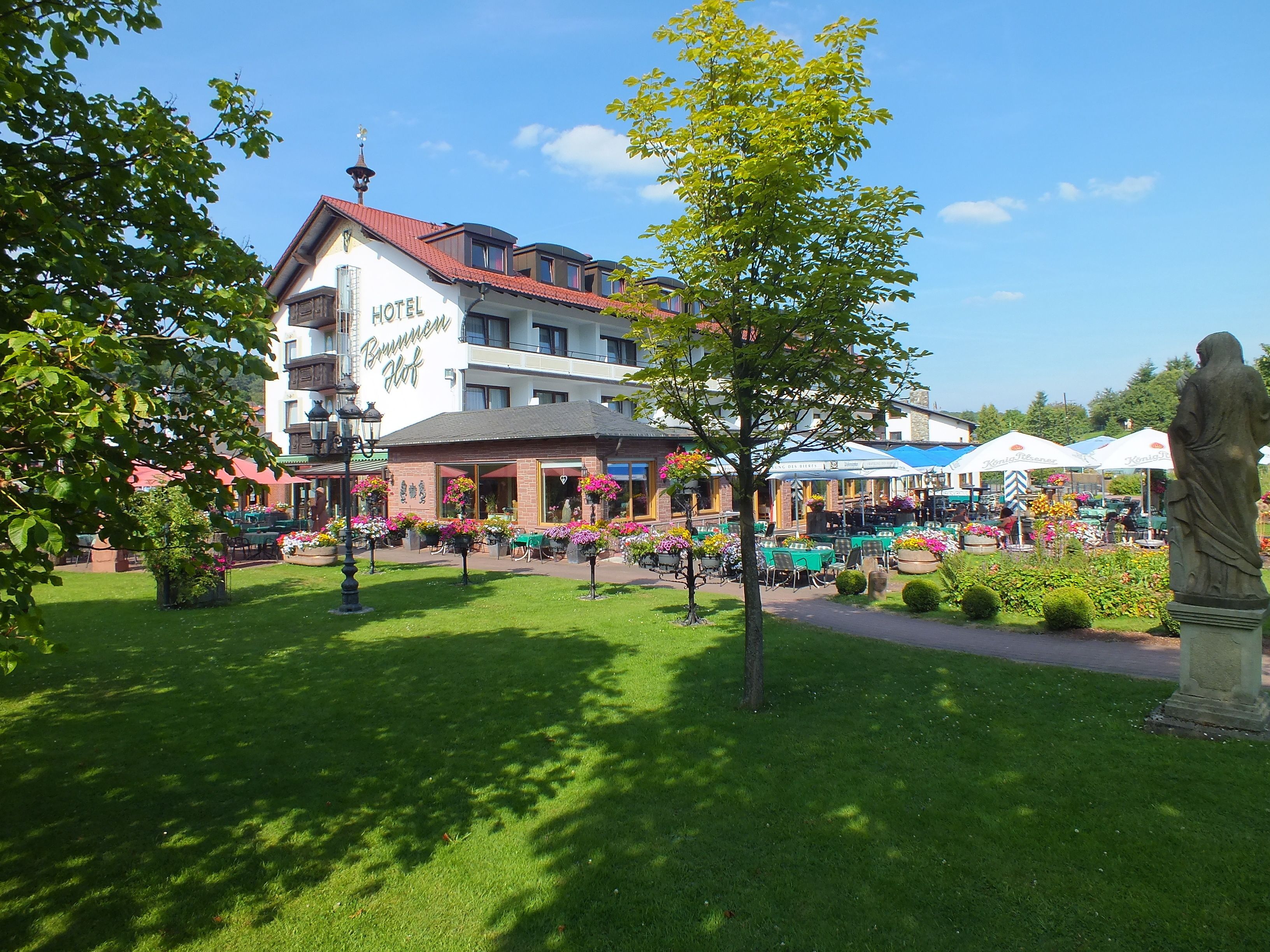 Un hotel con tejado rojo y un letrero que dice "HOTEL Brunnenhof".