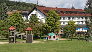 Un hotel con techo rojo, un parque infantil con un tobogán y una casita de juegos.