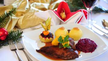 A plated meal with a fish, potatoes, and red cabbage, accompanied by a glass of red wine.