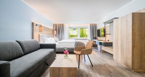 Una habitación de hotel moderna con una cama, un sofá, un escritorio y un televisor.