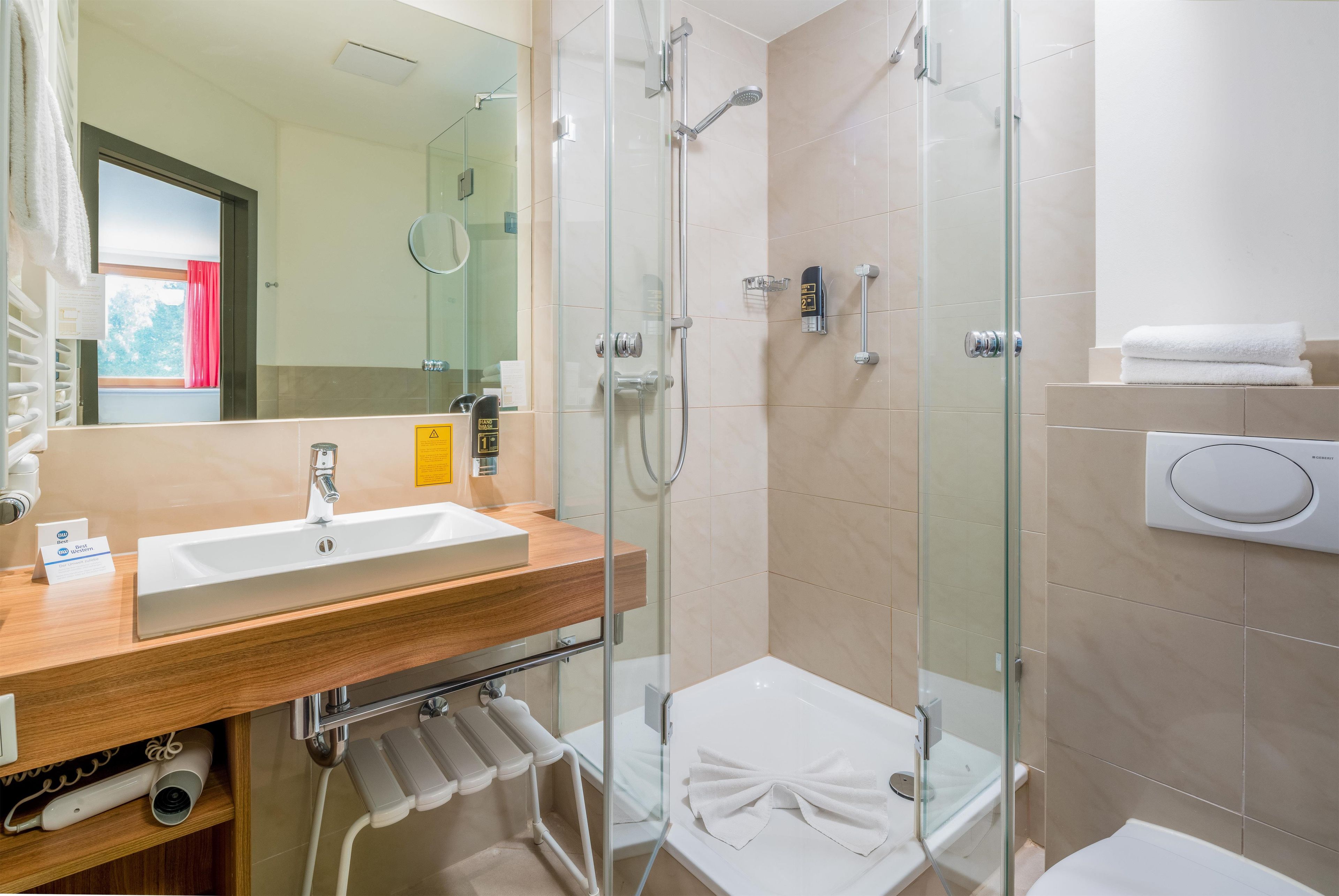 A modern bathroom with a glass shower enclosure, a white sink, and a toilet.
