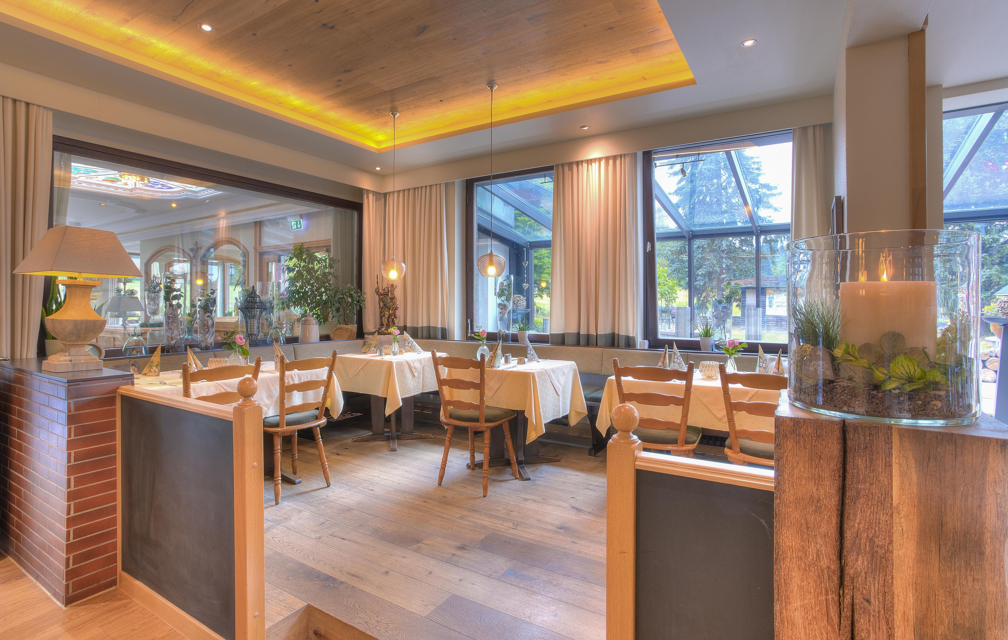 A restaurant with wooden flooring, tables with white tablecloths, and chairs.