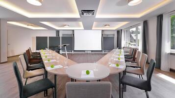 A conference room with a long table, chairs, a projector screen, and a large window.