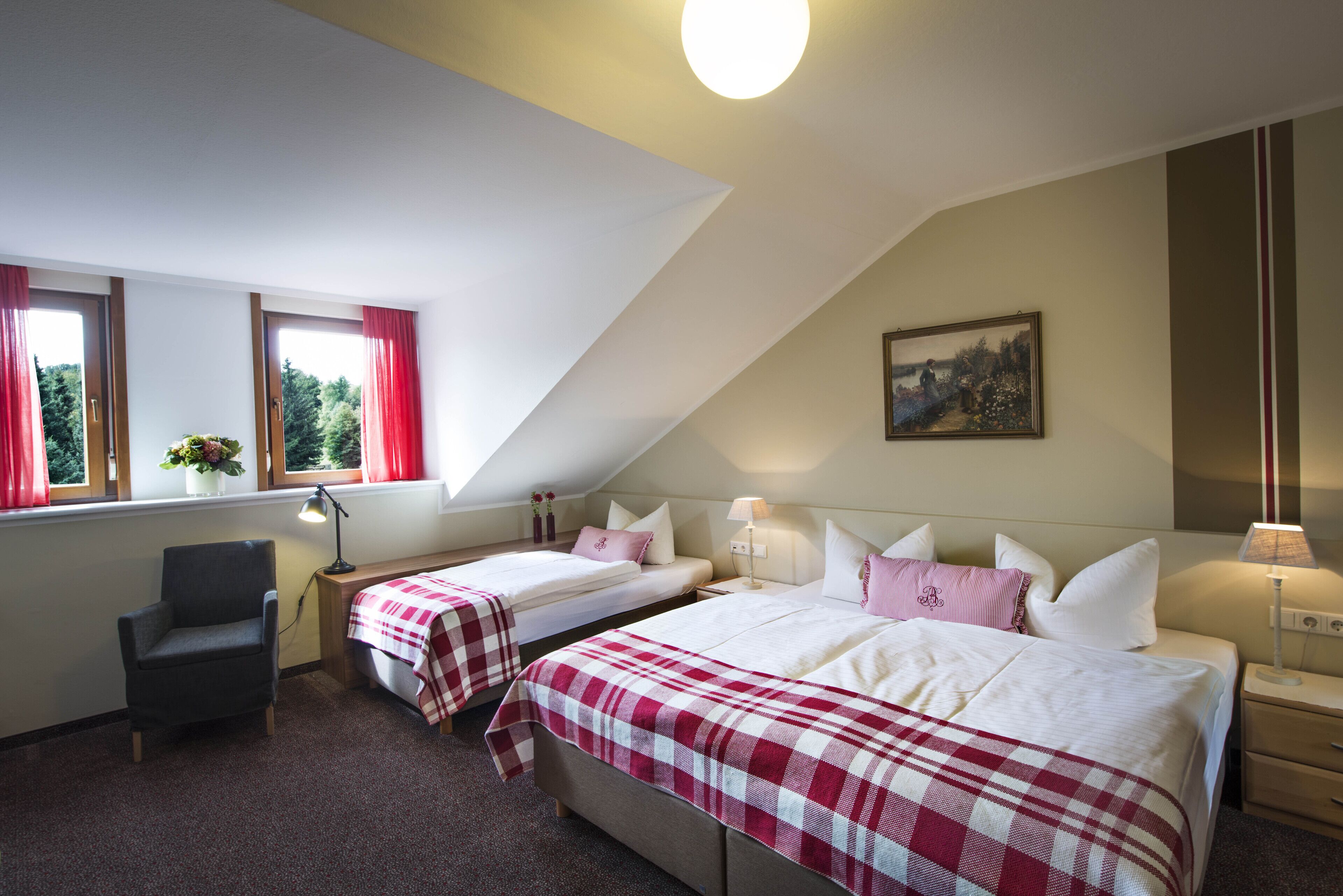 Une chambre avec deux lits, une chaise, un bureau, une fenêtre avec des rideaux et un tableau au mur.