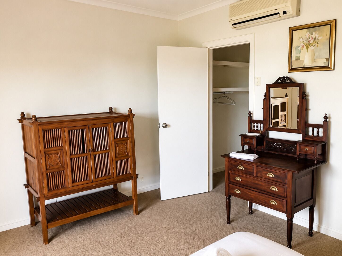 A bedroom with a wooden dresser, a mirror, and a white door leading to a closet.