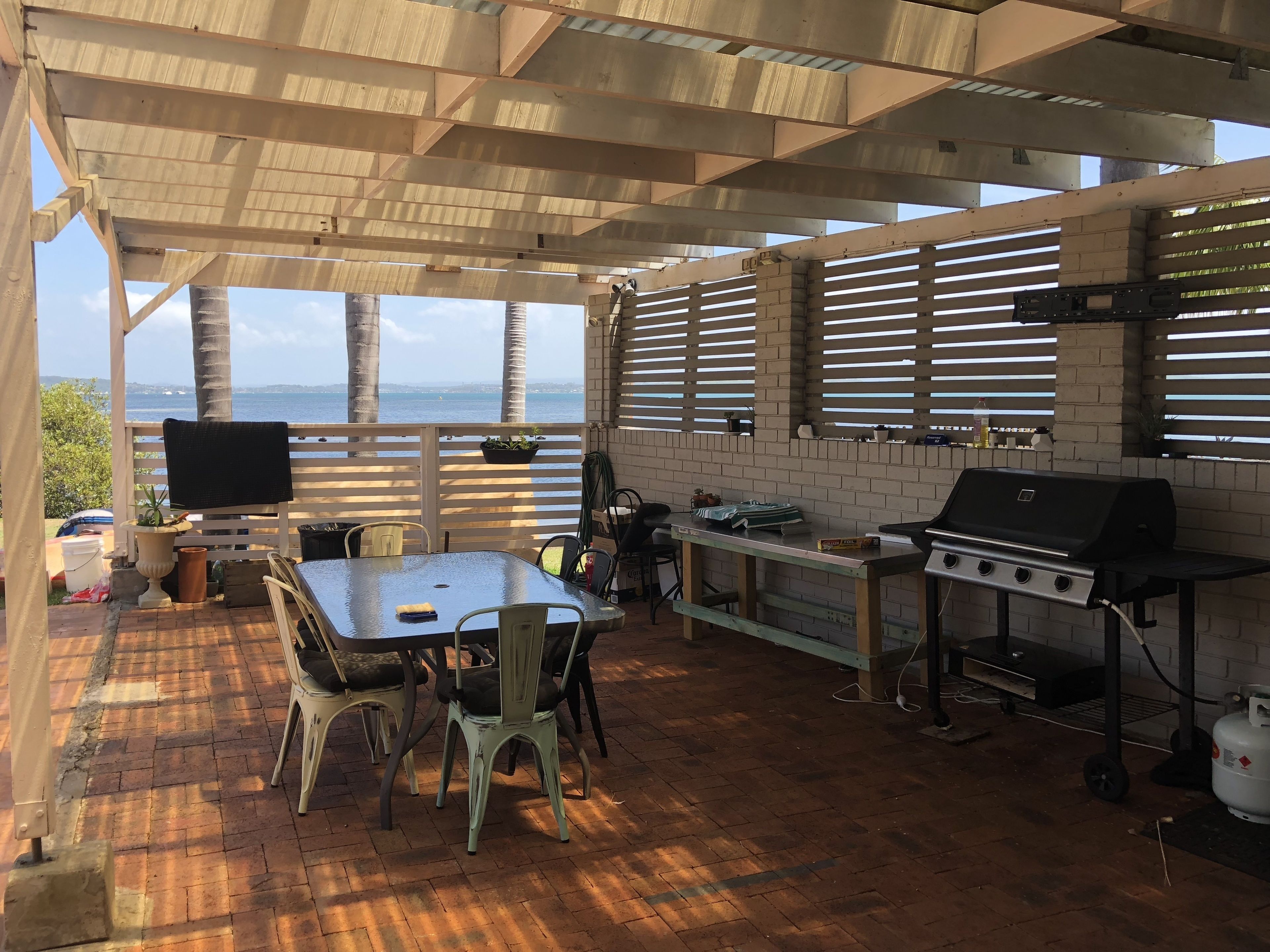 Un patio al aire libre con mesa y sillas, una parrilla y vistas al océano.
