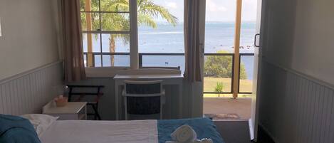 Une chambre d’hôtel avec un lit, un bureau et une vue sur la mer.