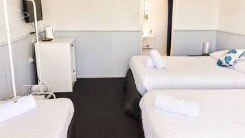 Ett hotellrum med två sängar, ett litet skrivbord, en TV och en duschhörna.