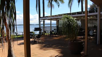 Relax in a serene outdoor setting with a covered patio, comfortable seating, and a beautiful view of the water.