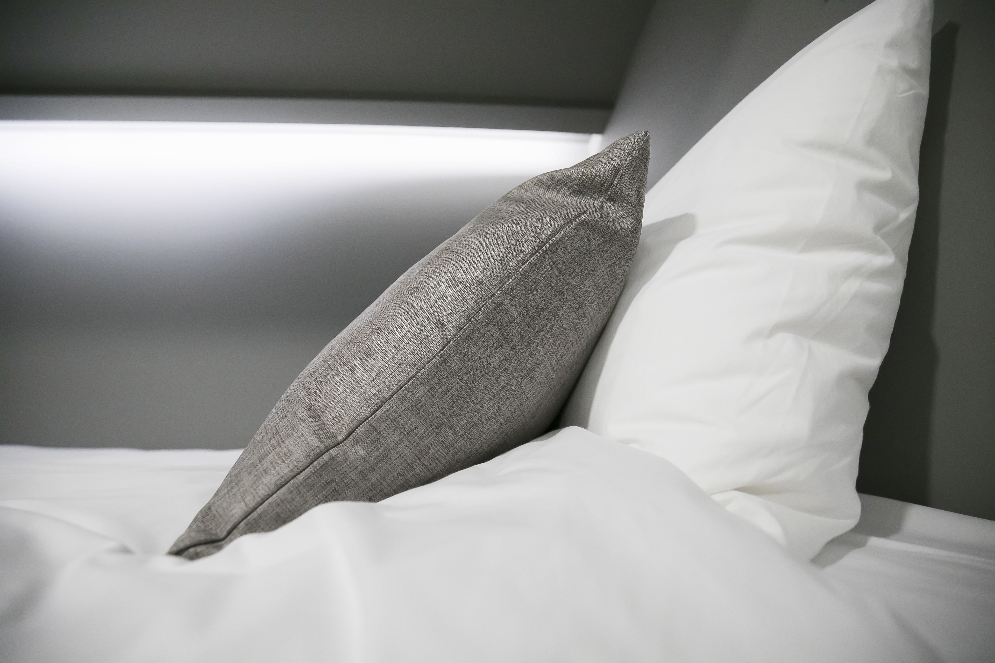 Un lit avec un oreiller gris et un oreiller blanc.