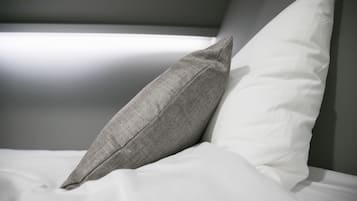 Un lit avec un oreiller gris et un oreiller blanc.