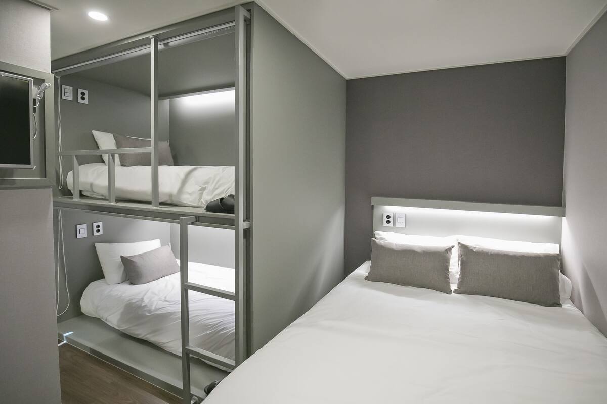 Una habitación de hotel con literas, una cama individual y un televisor.